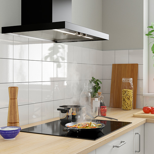 Cocina moderna con estufa de inducción, verduras coloridas, mostrador de madera y placa para salpicaduras gris.