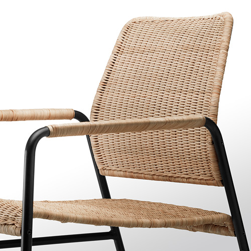 Primer plano de un sillón de ratán tejido que muestra un tejido intrincado y un marco de metal negro duradero.