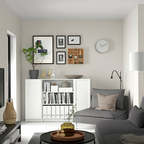 Sala de estar moderna con estantería BILLY blanca, sofá gris, mesa de centro, planta y reloj de pared.