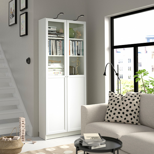 Salón moderno con librería BILLY, sofá beige, mesa de centro negra, escalera.