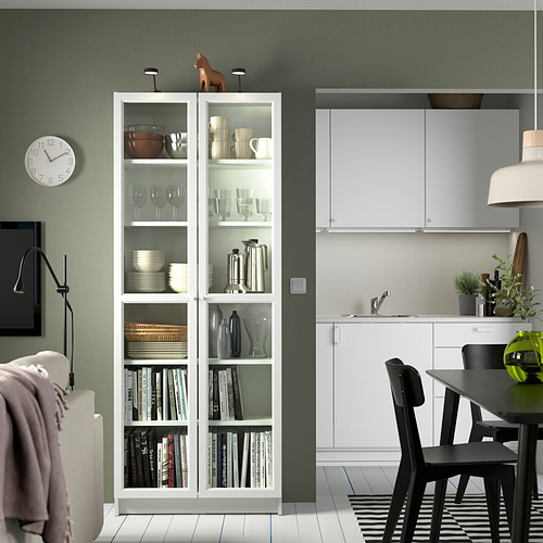 Sala de estar moderna con librería BILLY, pared verde, sillas negras.