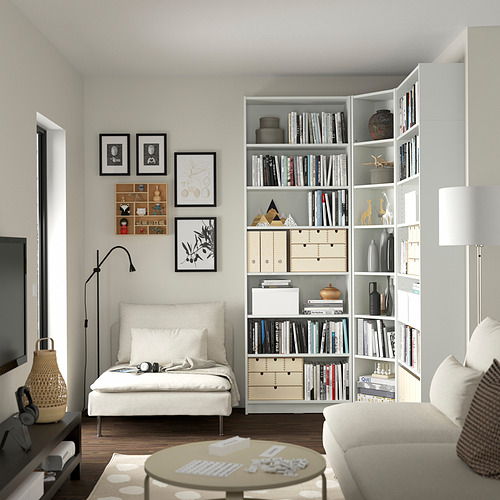 Sala de estar moderna con estanterías blancas BILLY, un sofá blanco y una lámpara de pie negra. Las estanterías tienen libros, jarrones y artículos decorativos.