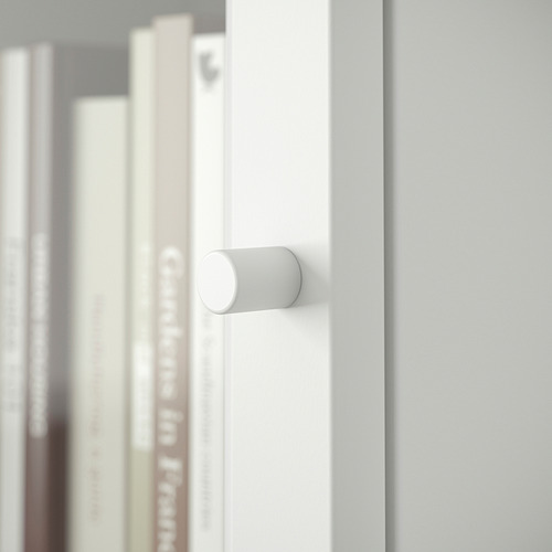 Un primer plano de un asa de estantería blanca BILLY, con libros borrosos en el fondo.