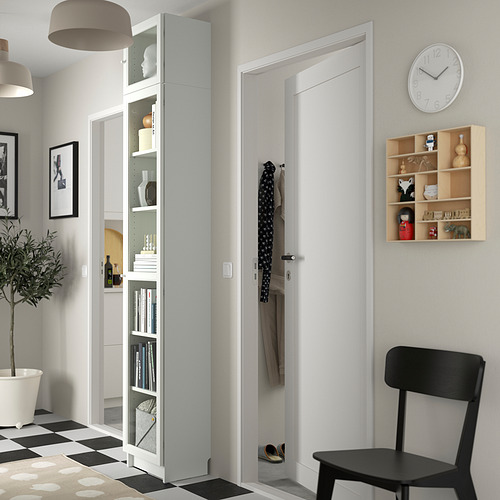 Entrada minimalista con estantería BILLY blanca, silla negra, reloj y abrigos colgantes.