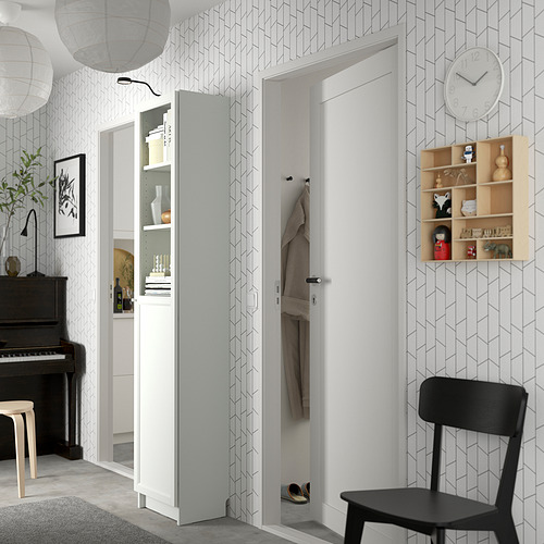 Pasillo moderno con librería blanca BILLY, silla negra, papel pintado geométrico, piano y reloj.