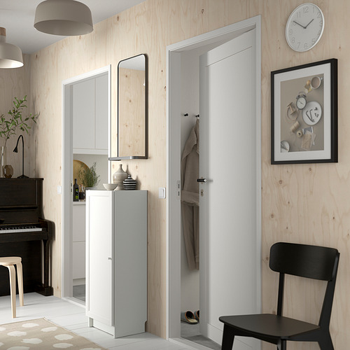 Pasillo moderno con gabinete blanco BILLY, espejo, silla negra, percheros, reloj de pared y piano. Paredes de madera clara, diseño minimalista.