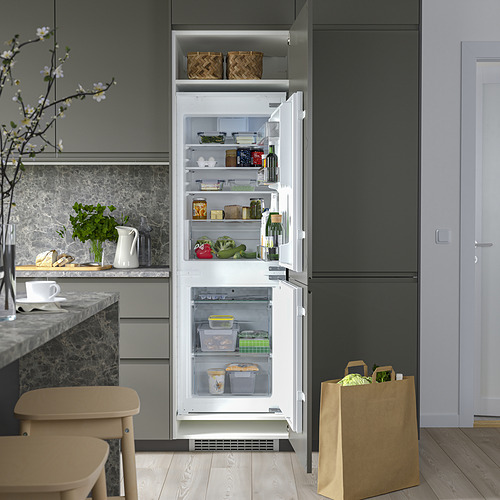 Refrigerador abierto con estantes ajustables, luz led y compartimentos transparentes. Verduras, frascos y bebidas visibles.
