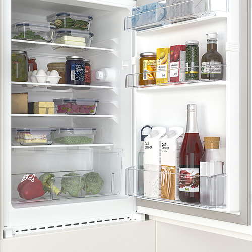 Una mini nevera bien organizada con compartimentos transparentes, que muestra verduras frescas, frascos y bebidas. Los estantes ajustables maximizan el almacenamiento.