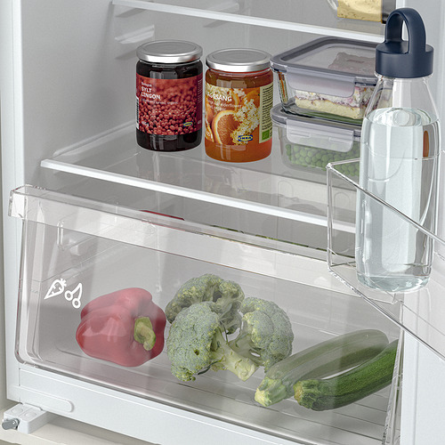 Una nevera con estantes ajustables con frascos, verduras y una botella de agua.