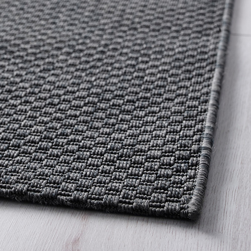 Primer plano de la textura tejida de las alfombras MORUM, mostrando su duradero material gris.