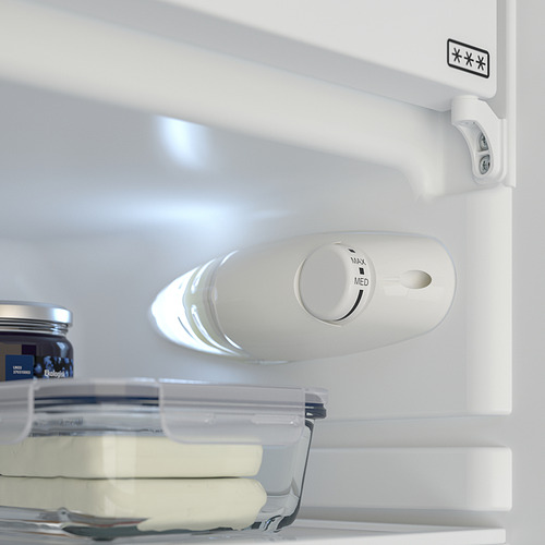 Un refrigerador abierto con luz led encendida. Un dial para el control de la temperatura. Se ve un recipiente de almacenamiento transparente con mantequilla.