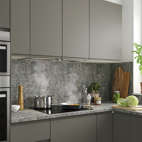 Cocina moderna con gabinetes grises, estufa negra, campana de acero inoxidable, placa para salpicaduras de mármol y utensilios y vegetación de encimera.