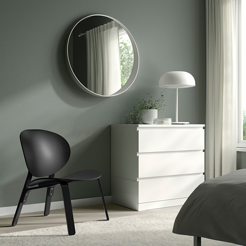 Dormitorio minimalista con silla, tocador, espejo, lámpara de seta, paredes de color verde claro.