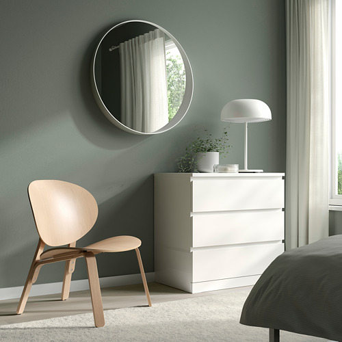 Dormitorio minimalista con silla de madera, tocador blanco, espejo redondo, lámpara, planta y cama. La silla escandinava FRÖSET realza el ambiente moderno.