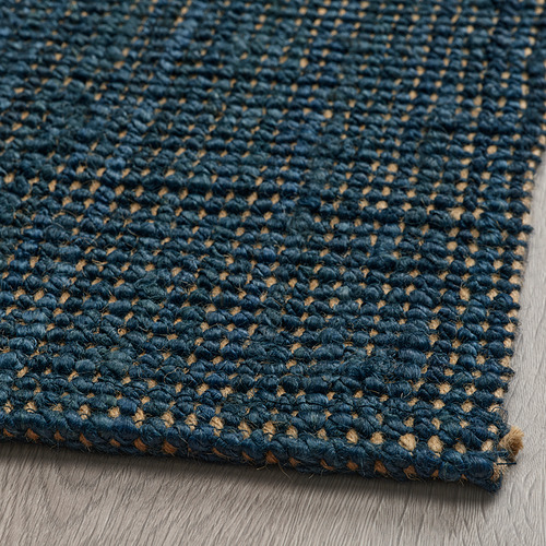 Alfombra texturizada de yute azul oscuro, de tejido liso, expuesta sobre suelo de madera.