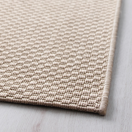Textura de color beige, alfombra intrincadamente tejida, plana y finamente cosida.
