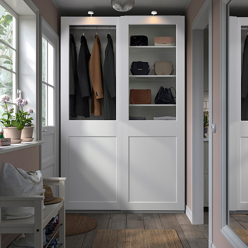 Armario moderno PAX con puertas de cristal, ropa, accesorios y toallas.