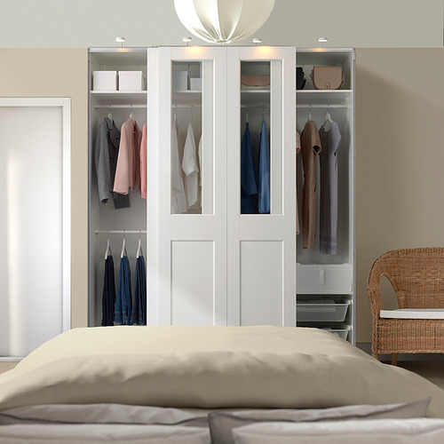 Dormitorio moderno con gran armario PAX blanco y puertas correderas de cristal. Silla de mimbre junto a la cama, predomina el armario.