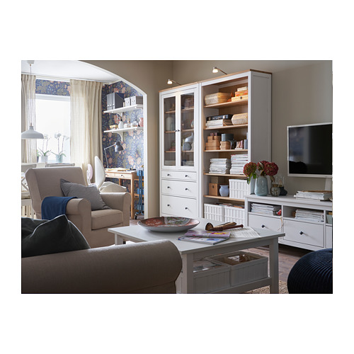 Sala de estar moderna con muebles beige, mueble de TV blanco y estantería de vidrio, con luz natural y una decoración acogedora.