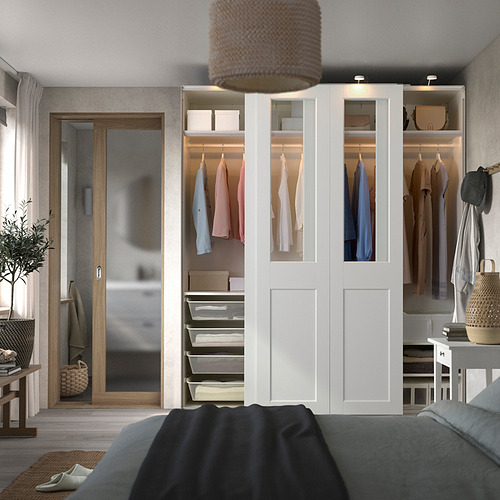 Armario blanco PAX con paneles de cristal y ropa colorida, alto con puertas elegantes e iluminación.