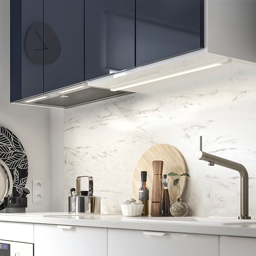 Cocina moderna con placa para salpicaduras de mármol, grifo de acero inoxidable y elegante campana extractora.
