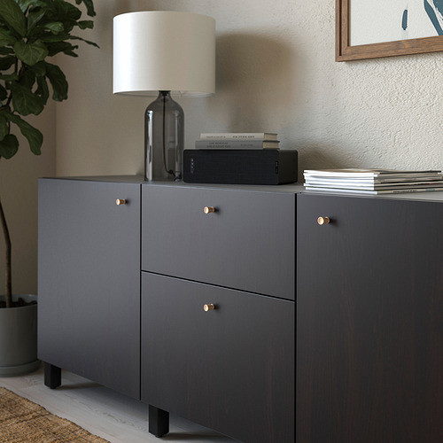 Moderno mueble gris con pomos de roble, rematado con lámpara, libros y altavoz.