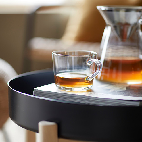 Taza de vidrio transparente en una bandeja, parte de la serie IKEA 365+, llena de líquido ámbar, probablemente té.