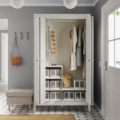 Moderno armario blanco con puertas plegables, ropa colgada, estantes y cajas de almacenamiento.