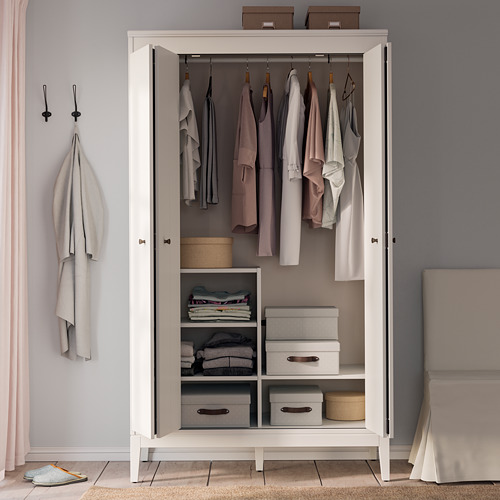 Armario blanco de IDANÄS, ordenado y organizado. Sostiene ropa y cajas, las puertas plegables ahorran espacio.