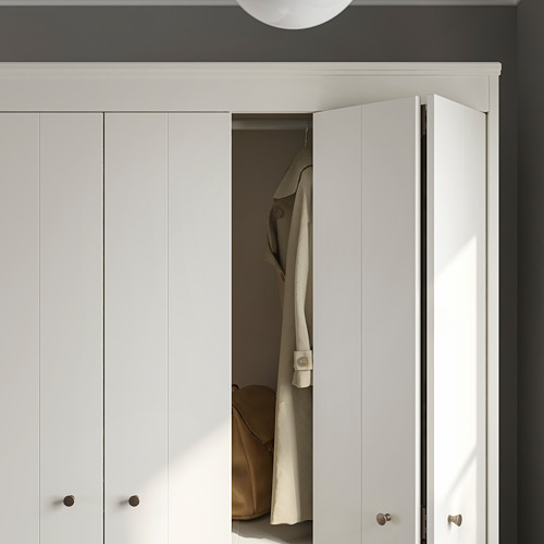 Armario blanco con puertas plegables, parcialmente abiertas, dejando al descubierto la chaqueta colgante. Diseño moderno y limpio.