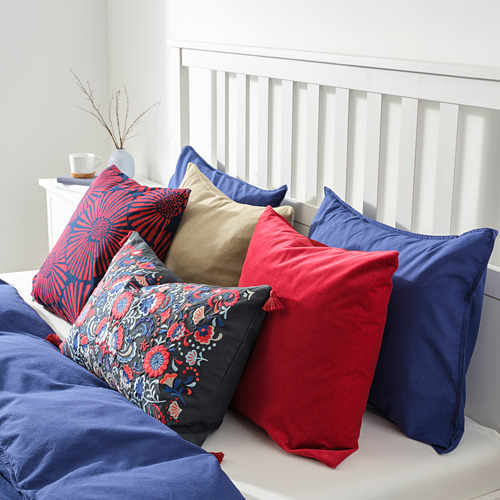 Cama con almohadas de colores. Cojines rojos, azules y estampados sobre colcha blanca.