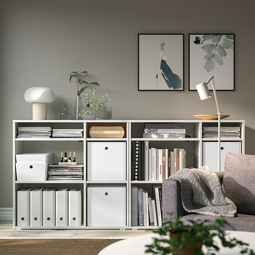 Espacio habitable minimalista con caja de almacenamiento KUGGIS, libros, decoración y obras de arte.