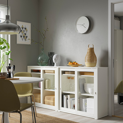 Modern dining area with white VIHALS cabinet, glass doors, and sleek design, fitting between chairs and near a gray wall.