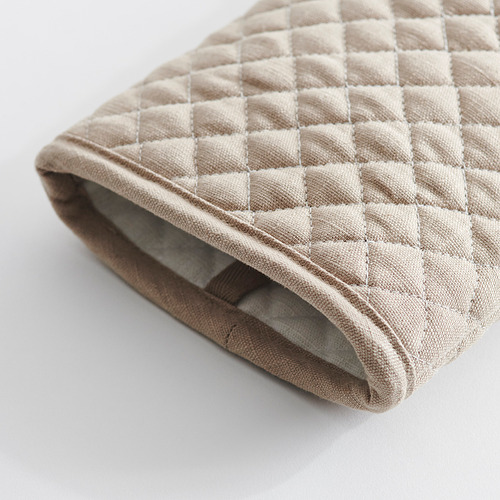 Almohada acolchada doblada sobre superficie blanca. Tejido suave con estampado de diamantes y costuras finas.