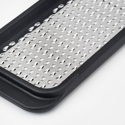Primer plano del rallador de acero inoxidable en marco de plástico negro, que muestra orificios afilados y espaciados uniformemente y un diseño duradero.