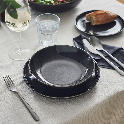 Plato de gres gris oscuro para una elegante mesa con cubiertos, vasos y servilletas.