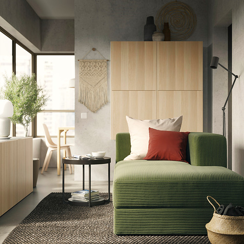 Sala de estar moderna con sofá modular JÄTTEBO verde, paneles de madera, accesorios tejidos y luz natural.