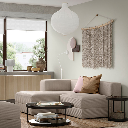 Sala de estar moderna con sofá modular JÄTTEBO beige, mesa auxiliar de madera, mesa de centro circular, lámpara colgante y arte de pared.
