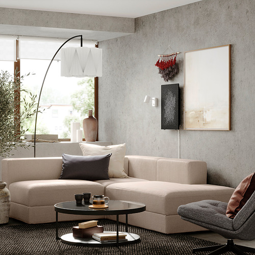 Sala de estar moderna con sofá seccional beige, mesa de café, silla gris, ventana grande y obras de arte abstractas.