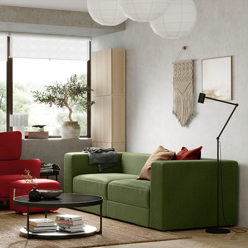 Sala de estar moderna con sofá JÄTTEBO verde oliva, sillas rojas, armarios de madera y lámpara de pie.