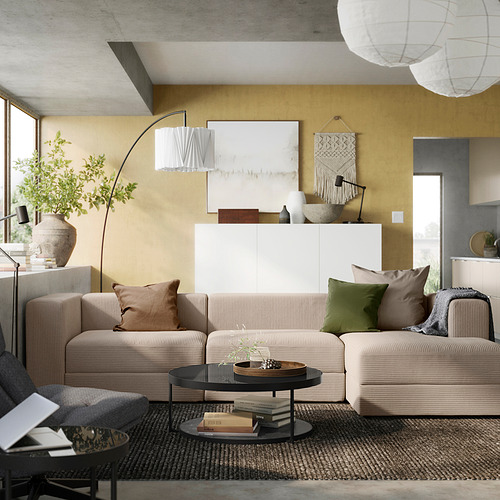 Sala de estar moderna con sofá seccional JÄTTEBO beige, paredes color mostaza y decoración acogedora.