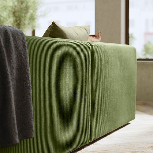 Sofá modular JÄTTEBO verde, textura acanalada, líneas limpias, cojines, suelo de madera, gato.