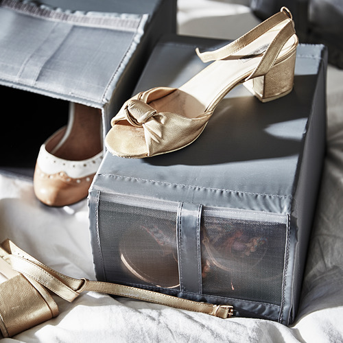 Tacones dorados con lazo, sobre caja de malla gris con cierre de velcro.