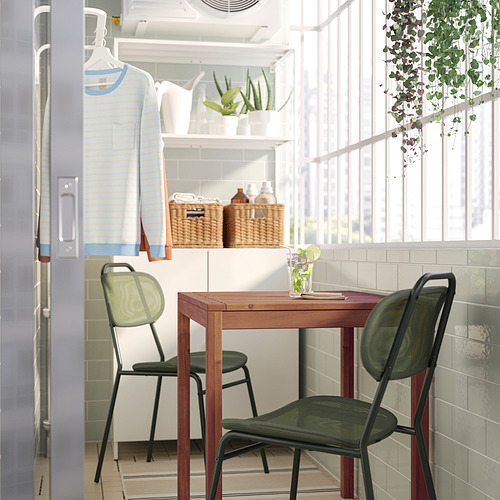 Conjunto de patio con mesa, tapa de vidrio, sillas de malla verde, plantas.