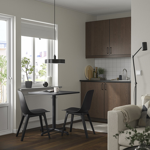 Modern kitchen with black STENSELE table and chairs, surrounded by cabinets and a window.