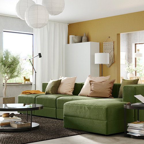 Sala de estar moderna con sofá JÄTTEBO verde, cojines beige, paredes mostaza y lámparas.