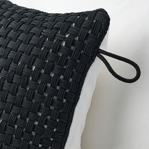 Detalle de cojín de exterior tejido a mano en color negro, con un tejido intrincado y un lazo duradero.