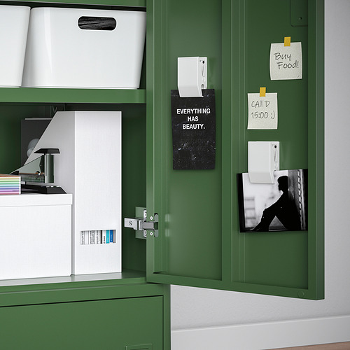Armario IDÅSEN verde con puerta abierta, que muestra cajas de almacenamiento, papeles y notas en la puerta.