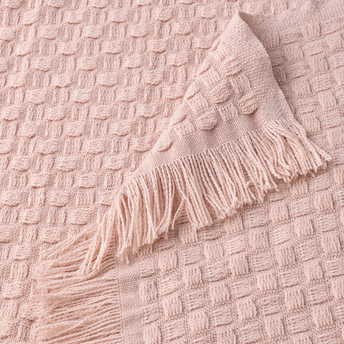 Manta suave de color rosa claro con tejido de cesta texturizado y divertidos flecos, confeccionada en poliéster reciclado.