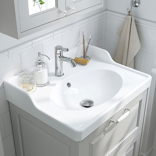 Lavabo de baño limpio y minimalista con grifo cromado, dispensador de jabón y soporte para cepillos de dientes.